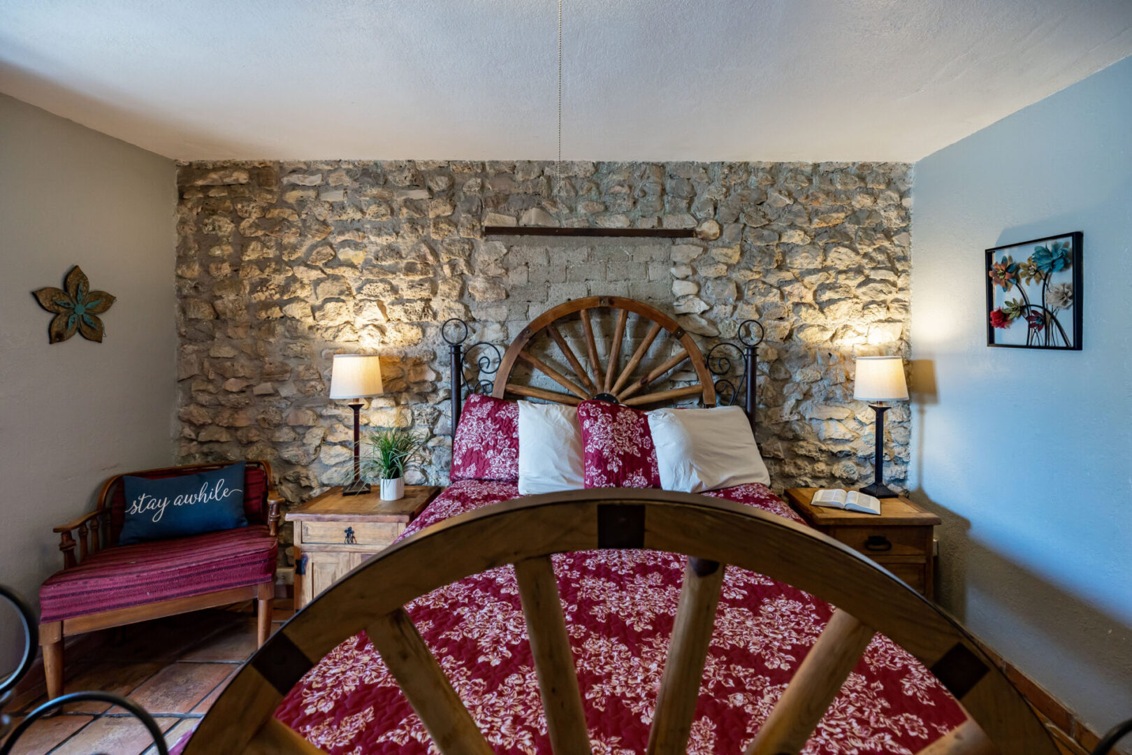 A room with a stone wall design and a bed with pink sheets.