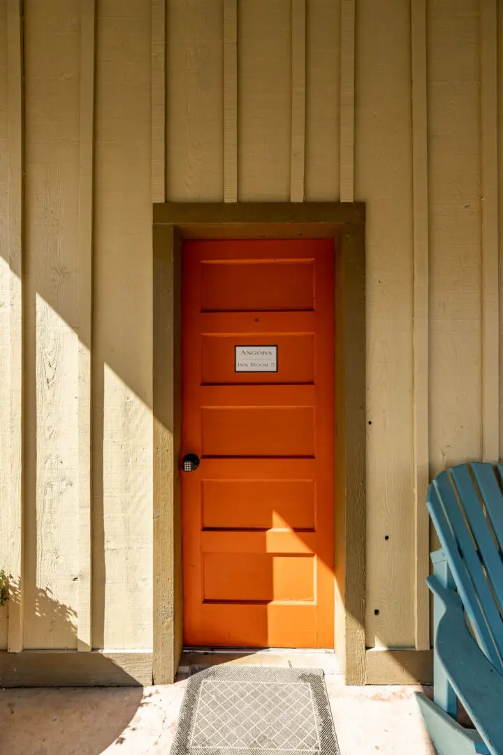 A orange door from the outside with sun rays coming from the side